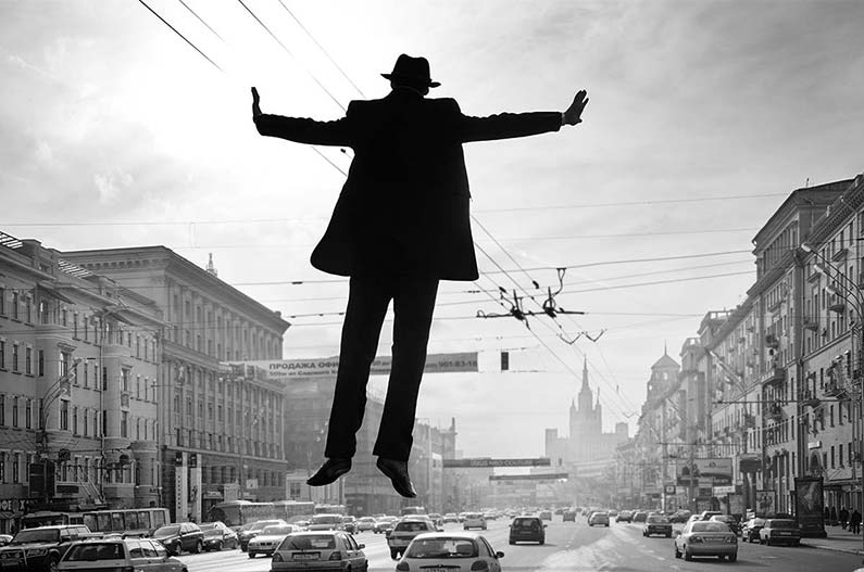 A figure floating over a city street.